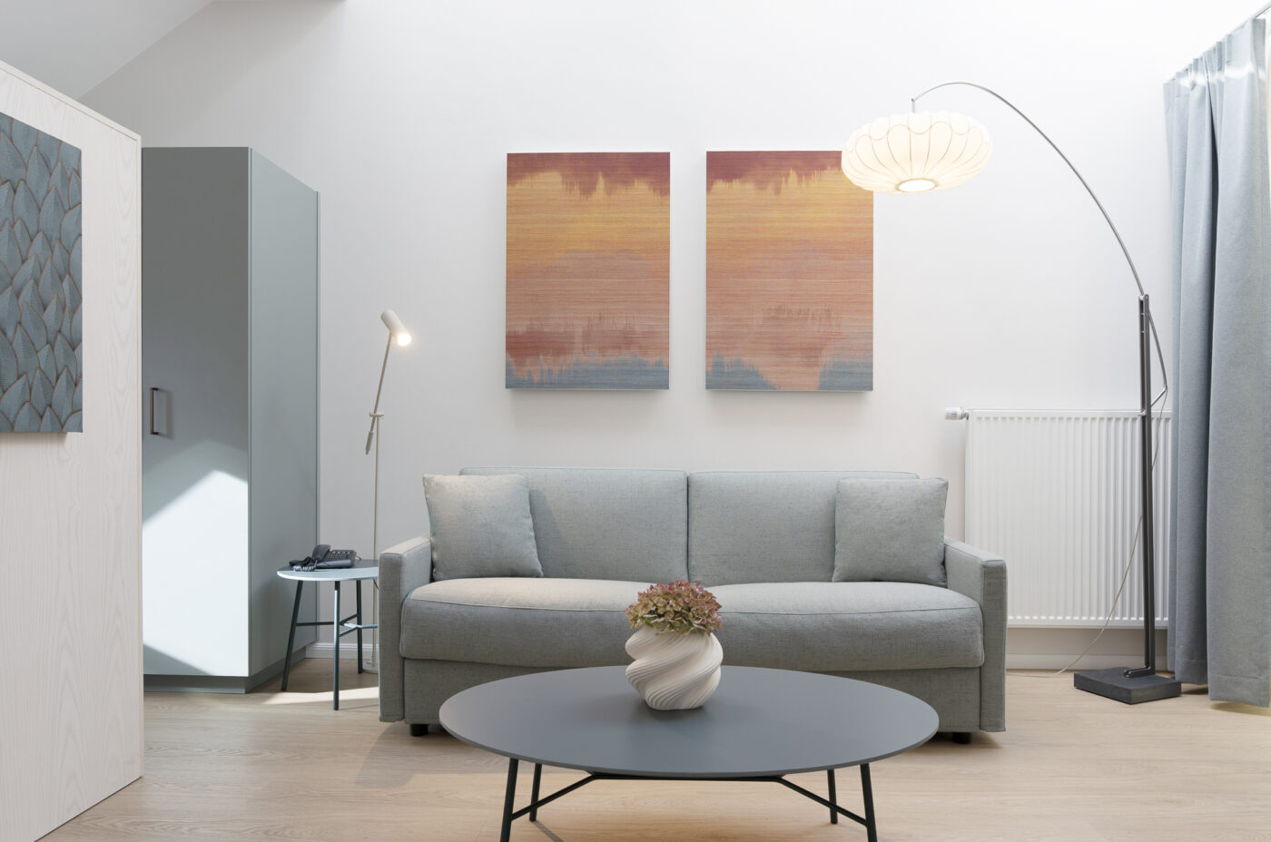 Keyinn Serviced Residences Belair living room with a light grey sofa and abstract wall art. The space includes sleek lamps, warm lighting, and a modern design.