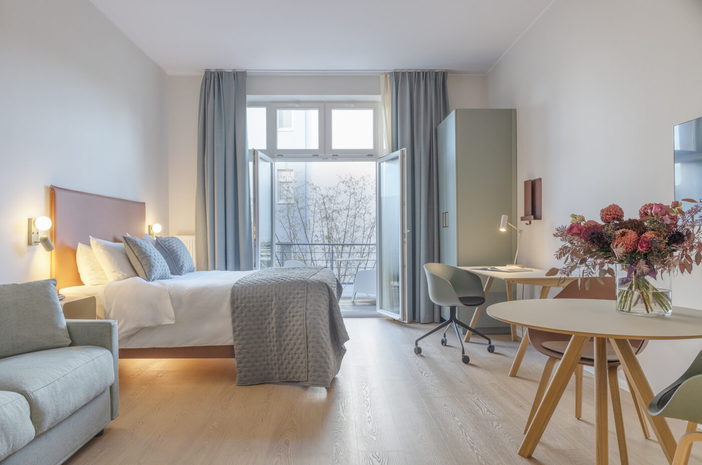 Keyinn Serviced Residences Belair studio with a bed, sofa, and dining table. The space includes a balcony, city views, and a bright, modern design.