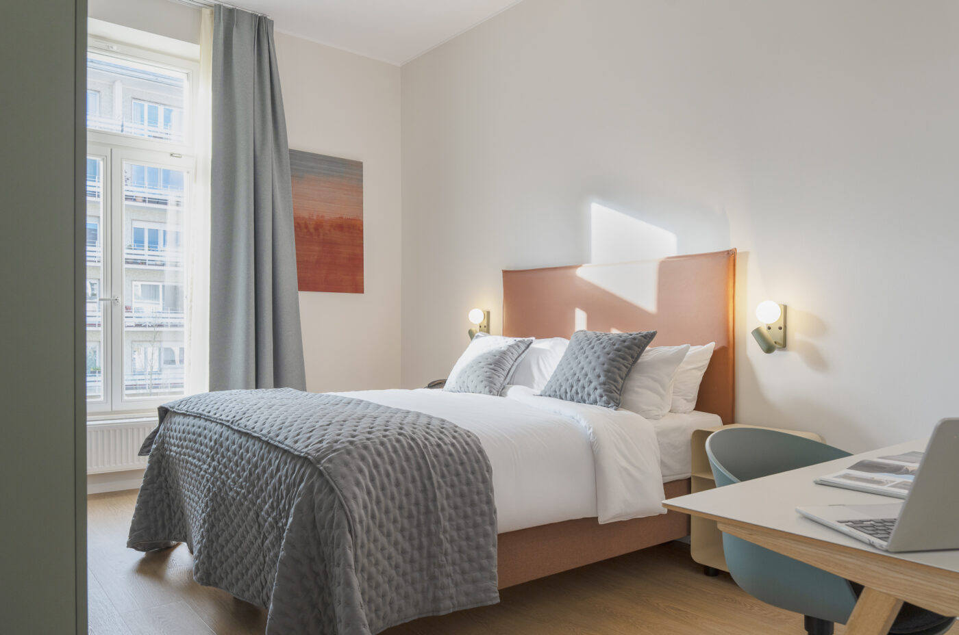 Keyinn Serviced Residences Belair room with a neatly made bed, gray accents, and soft lighting. The space features a window with city views and a modern design.