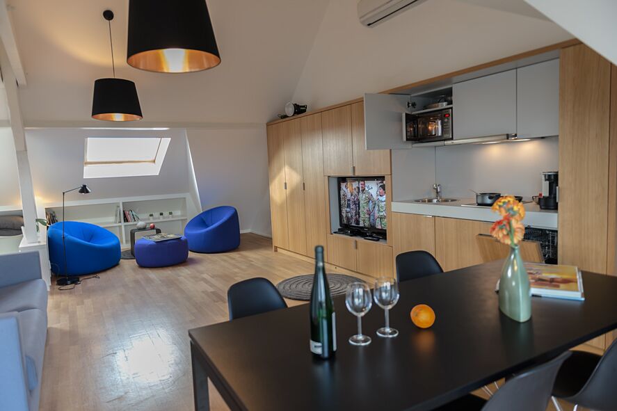 Keyinn Serviced Residences Parc de Merl loft living space with wooden flooring, kitchenette, and blue bean seating.