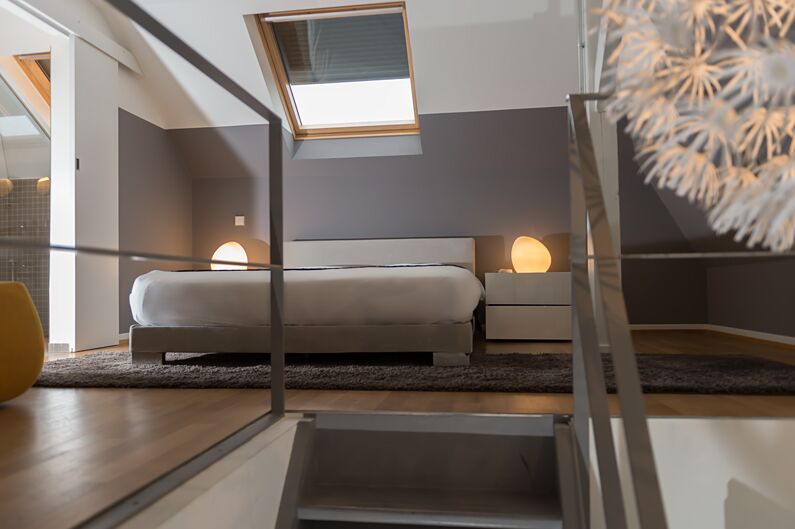 Keyinn Serviced Residences attic bedroom in Limpertsberg, with a double bed, skylight & spherical lamps.
