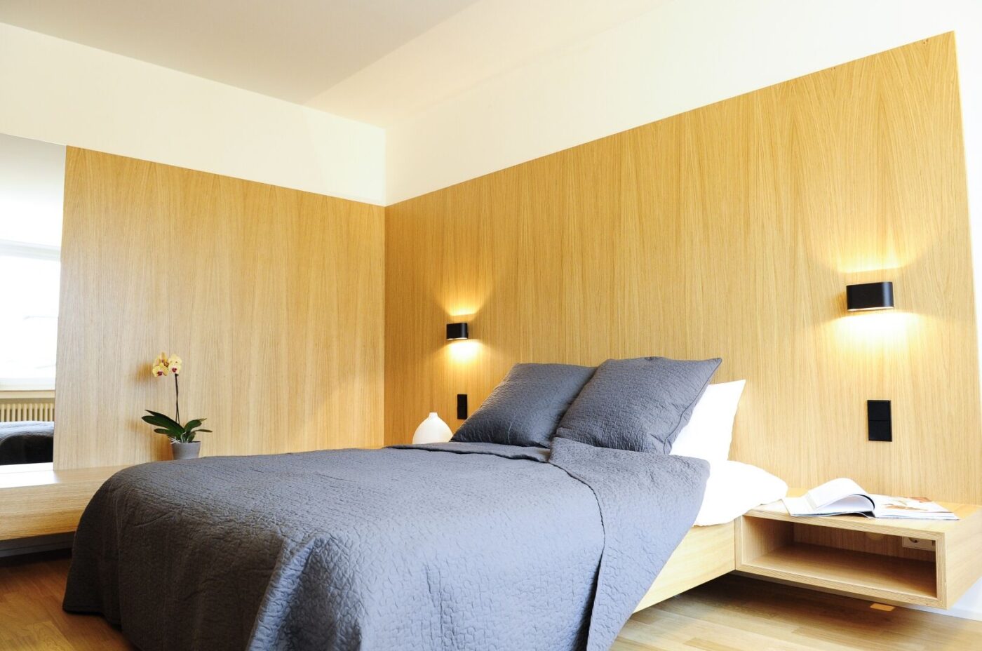 Keyinn Serviced Residences Parc de Merl bedroom with wood-panelled accents, & grey bedding
