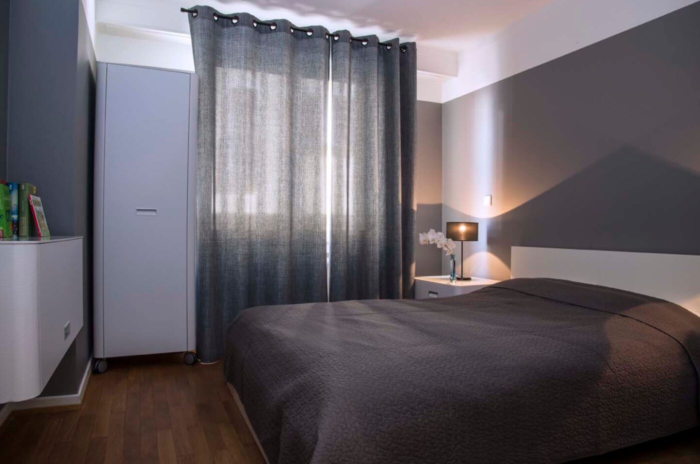 Keyinn Serviced Residences Limpertsberg bedroom with a dark quilt, grey walls, and matching curtains.