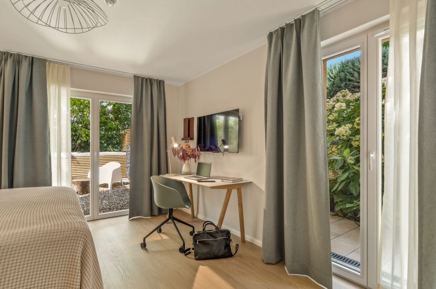 Modern room at Keyinn Serviced Residences with a beige bed, light wooden floor, and a desk with a laptop.
