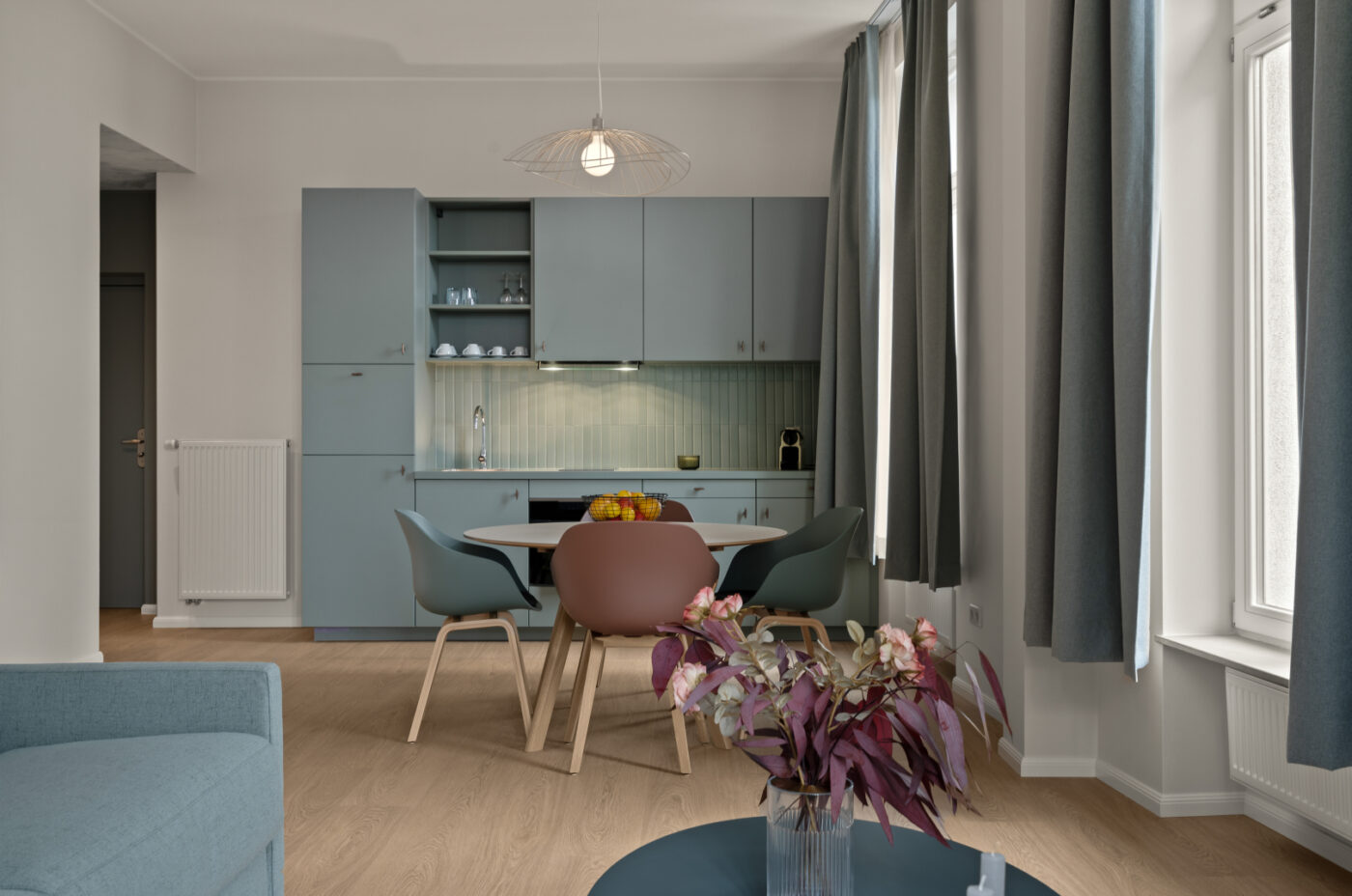 Keyinn Serviced Residences kitchen-living area with light blue cabinets, wooden dining table, and chairs.