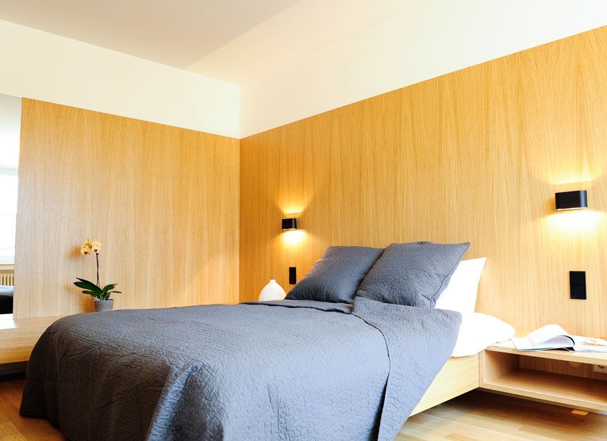 Keyinn Serviced Residences bedroom with a wooden accent wall, gray bedding, and a potted orchid.