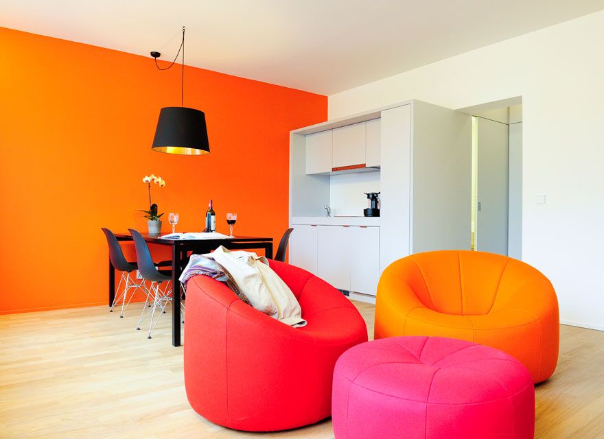 Keyinn Serviced Residences apartment with vibrant orange and red seating, a black dining table, and polished decor in Parc de Merl.